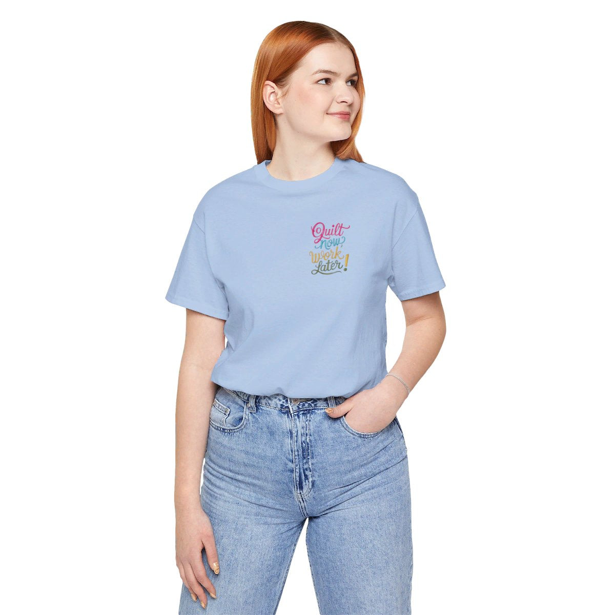 A Baby Blue funny quilting T-shirt featuring bold, stylized text that reads "Quilt Now, Work Later" in various vibrant colors. The playful design captures the spirit of passionate quilters who prioritize their craft over other responsibilities.