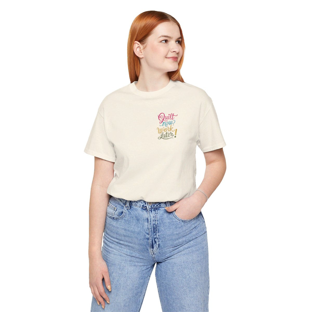 A Natural funny quilting T-shirt featuring bold, stylized text that reads "Quilt Now, Work Later" in various vibrant colors. The playful design captures the spirit of passionate quilters who prioritize their craft over other responsibilities.