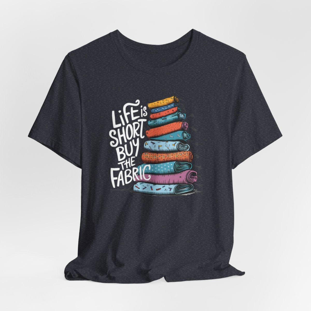 A Heather Navy fun T-Shirt with the phrase Life is Short, Buy the Fabric with the label 'Life is Short, Buy the Fabric' next to a graphic of a fun pile of fabric