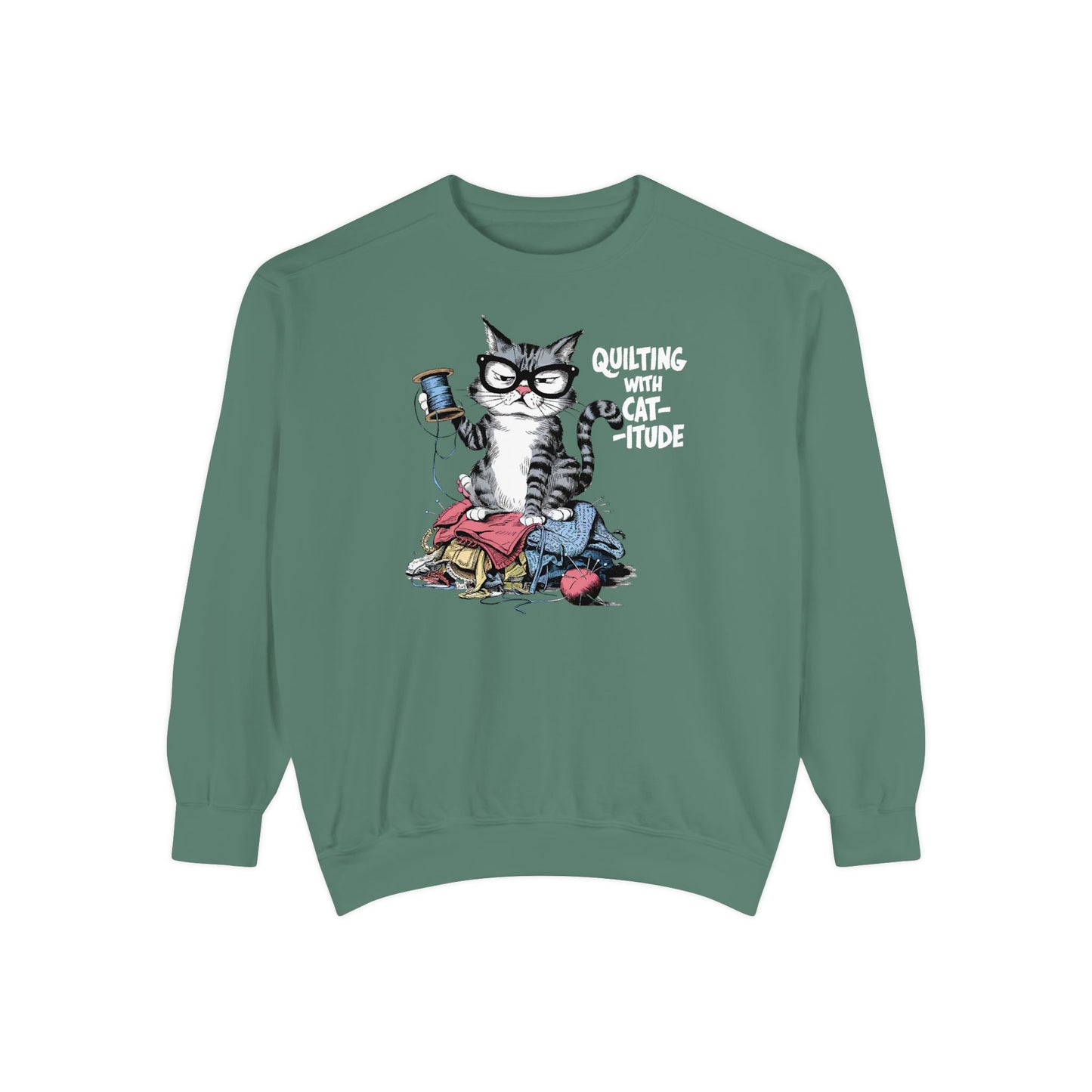 A Light Green sweatshirt featuring a sassy cartoon cat sitting on a pile of colorful fabric, holding a spool of thread, with the phrase 'Quilting with Cat-itude,' perfect for quilters and cat lovers.