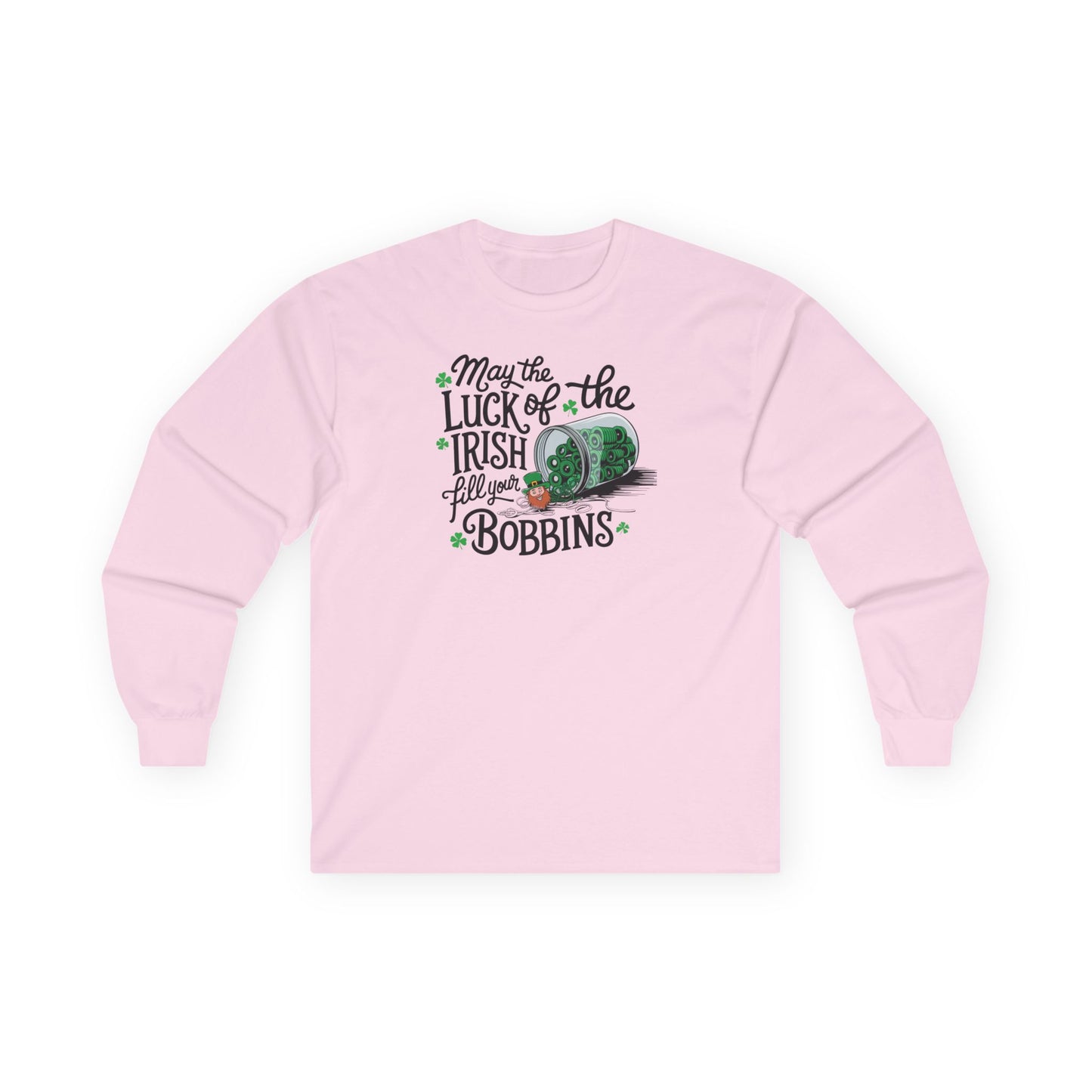 A Light Pink long-sleeve t-shirt featuring a festive design with shamrocks, a spool of green thread, and the phrase 'May the Luck of the Irish Fill Your Bobbins,' perfect for quilters celebrating St. Patrick’s Day.