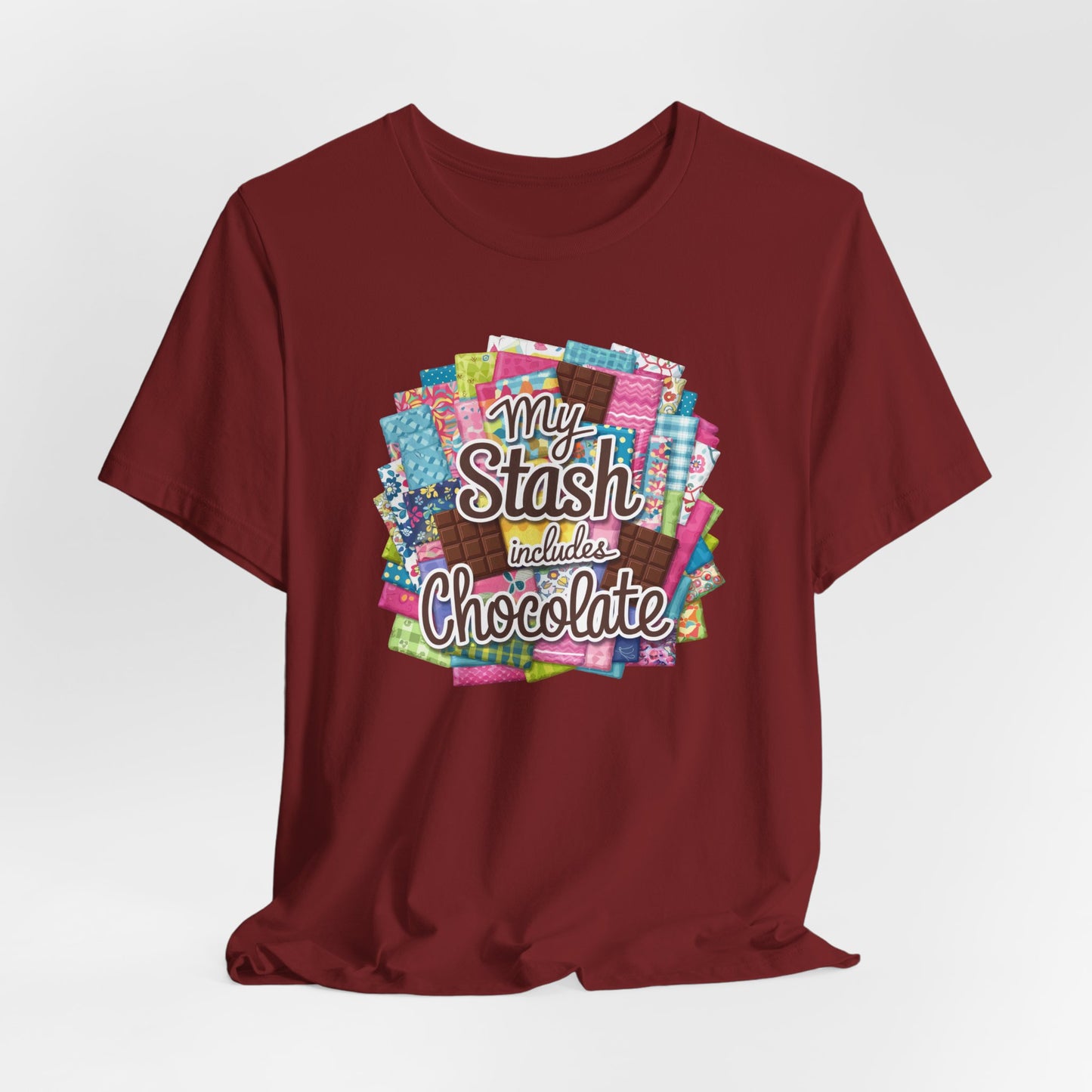 A Cardinal t-shirt featuring a colorful design of a fabric stash mixed with chocolate bars and the phrase 'My Stash Includes Chocolate,' perfect for quilters and chocolate lovers