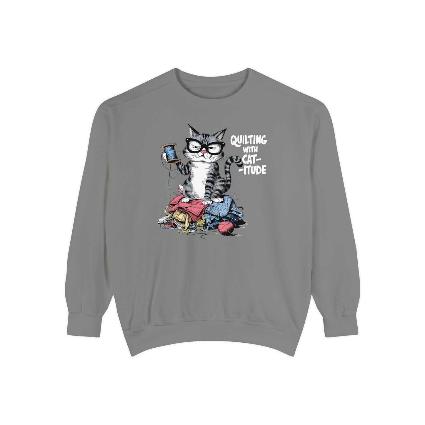 A Grey sweatshirt featuring a sassy cartoon cat sitting on a pile of colorful fabric, holding a spool of thread, with the phrase 'Quilting with Cat-itude,' perfect for quilters and cat lovers.