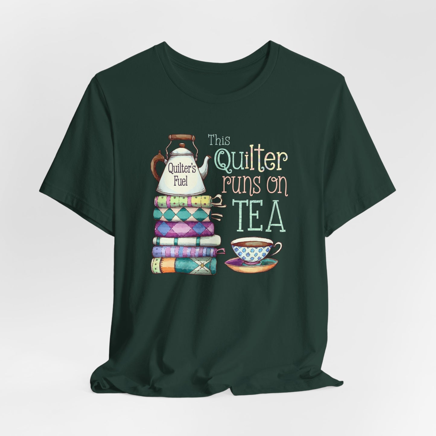 A Forest t-shirt featuring a whimsical design of a stack of patchwork quilts with a teapot labeled 'Quilter's Fuel' and the phrase 'This Quilter Runs on Tea,' ideal for tea-loving quilters.