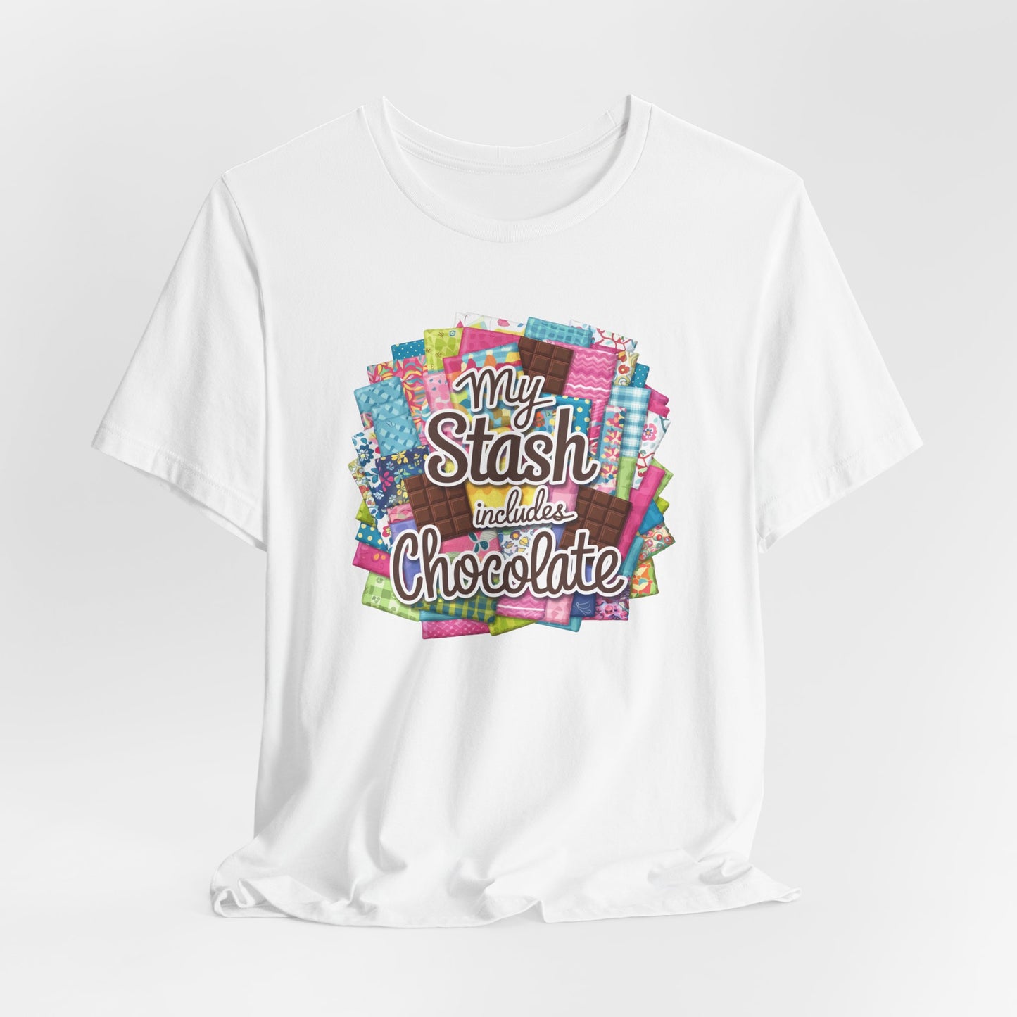 A White t-shirt featuring a colorful design of a fabric stash mixed with chocolate bars and the phrase 'My Stash Includes Chocolate,' perfect for quilters and chocolate lovers