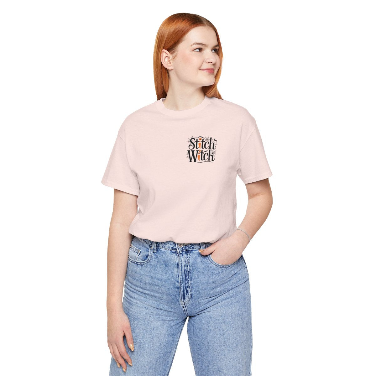 A Soft Pink Halloween Quilting T-Shirt featuring "Stitch Witch" text in Halloween-themed typography. Jack-o'-lanterns, spiderwebs, and bats decorate the letters. The "i" in "Stitch" resembles a sewing needle. Ideal for quilters who love Halloween.