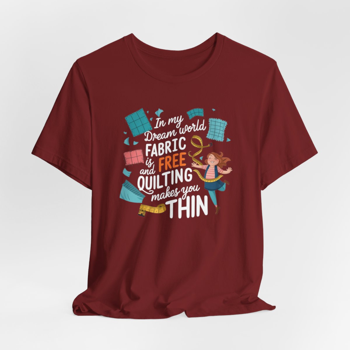 A Cardinal funny quilting T-Shirt with the phrase Fabric is Free and Quilting Makes You Thin in a fun font with a cheerful quilter jumping for joy