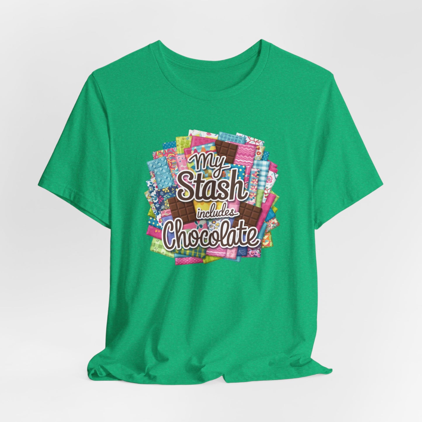 A Heather Kelly t-shirt featuring a colorful design of a fabric stash mixed with chocolate bars and the phrase 'My Stash Includes Chocolate,' perfect for quilters and chocolate lovers