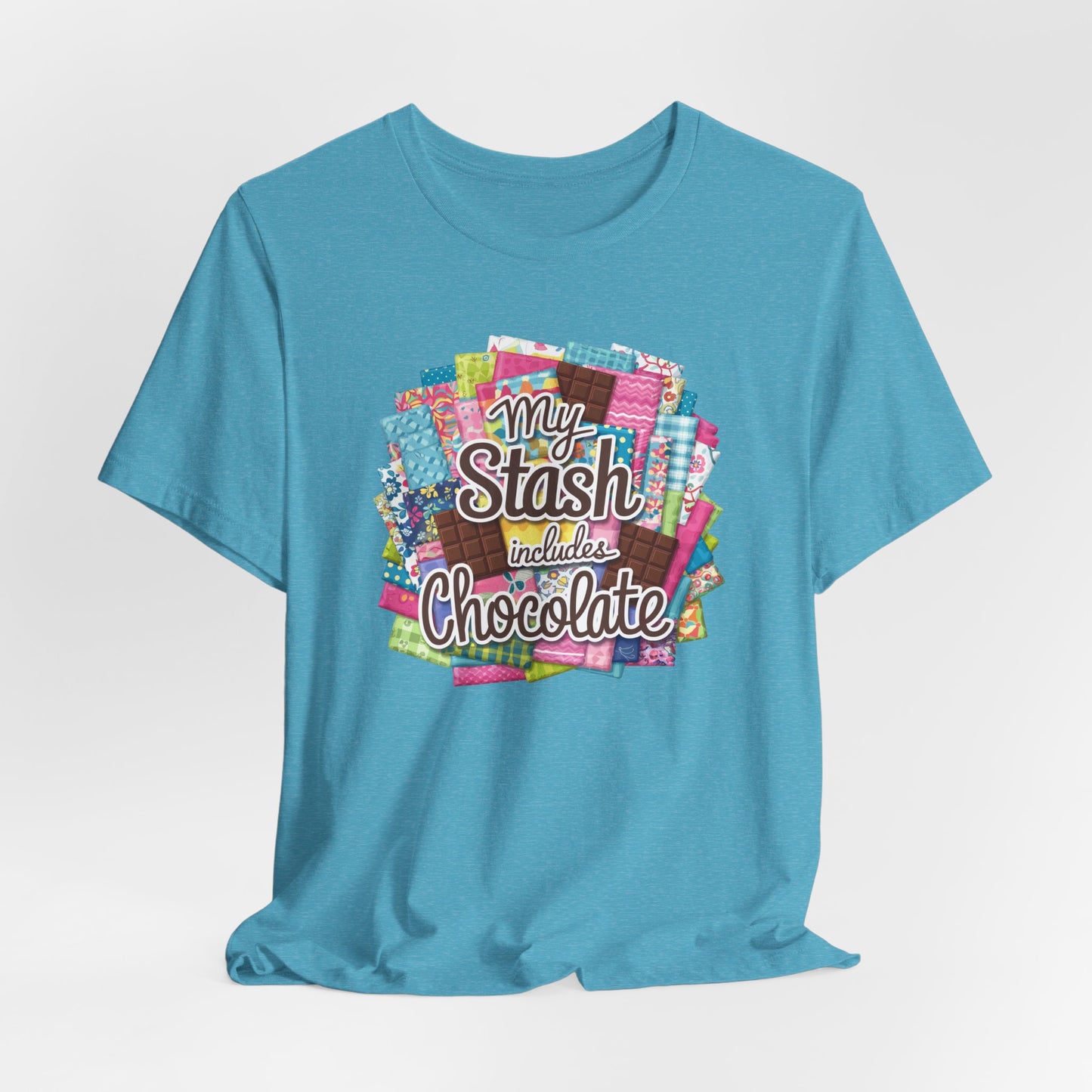 A Heather Aqua t-shirt featuring a colorful design of a fabric stash mixed with chocolate bars and the phrase 'My Stash Includes Chocolate,' perfect for quilters and chocolate lovers