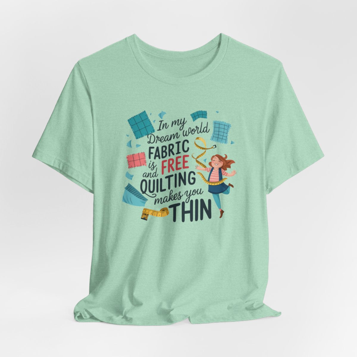 A Heather Mint funny quilting T-Shirt with the phrase Fabric is Free and Quilting Makes You Thin in a fun font with a cheerful quilter jumping for joy