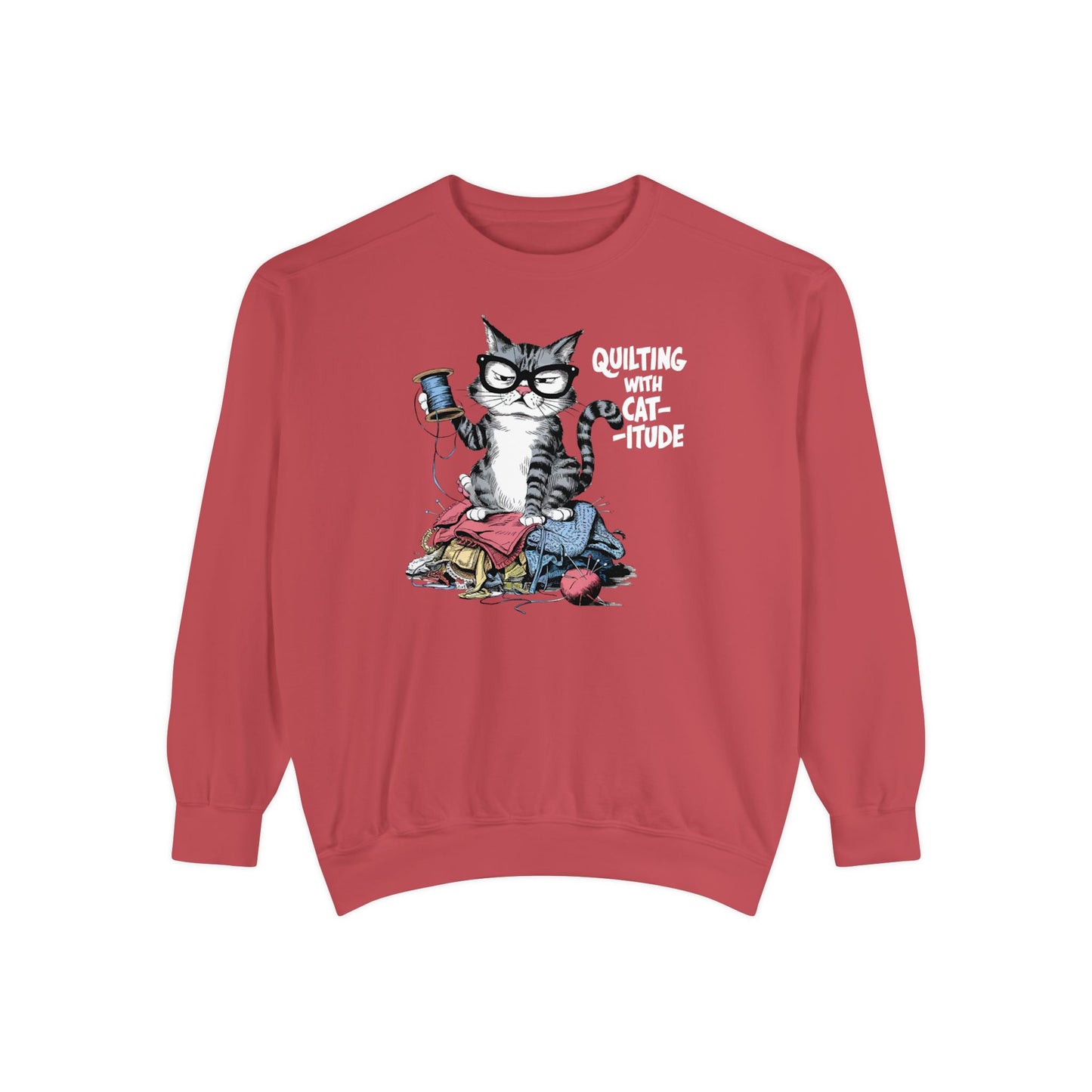 A Crimson sweatshirt featuring a sassy cartoon cat sitting on a pile of colorful fabric, holding a spool of thread, with the phrase 'Quilting with Cat-itude,' perfect for quilters and cat lovers.