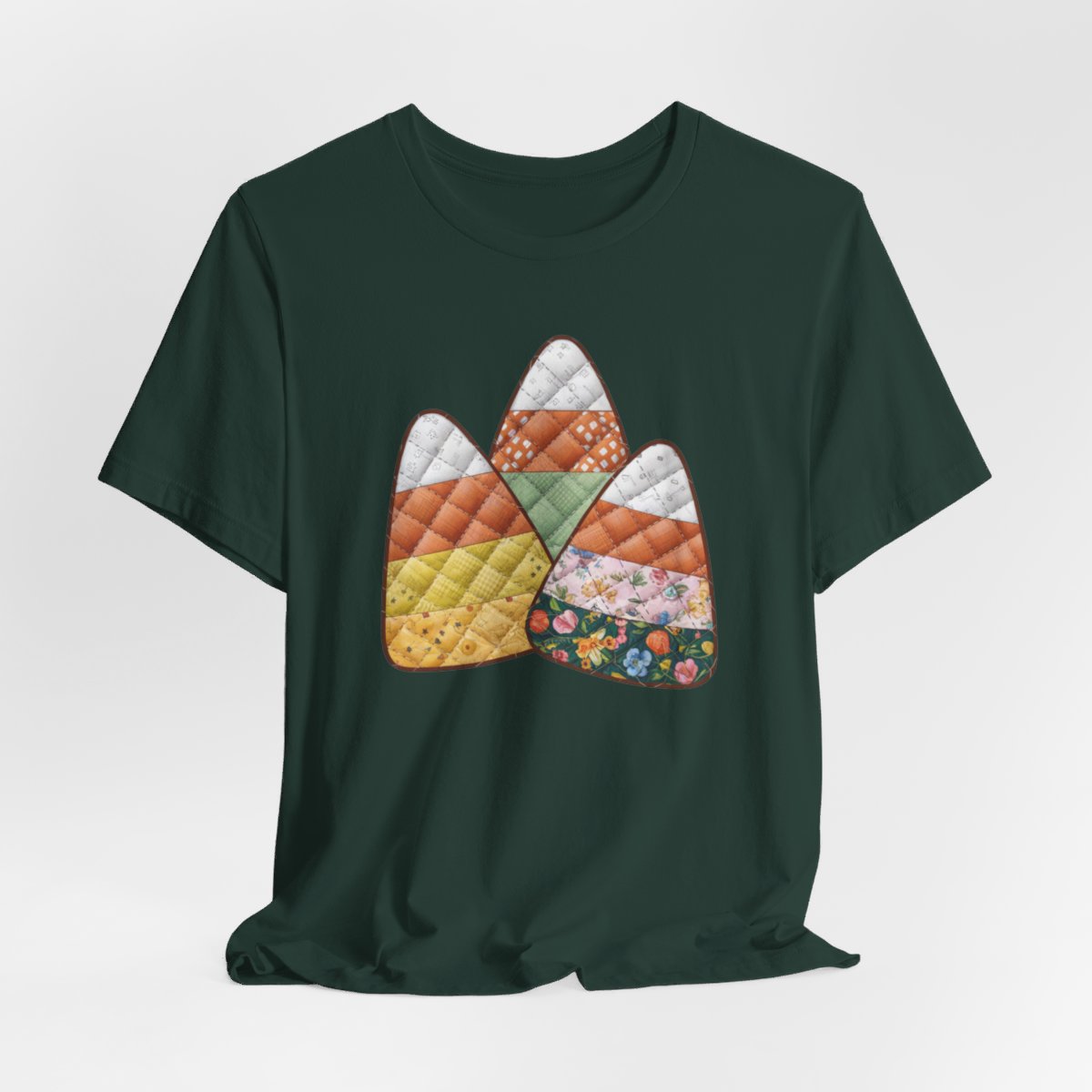 A Forest Halloween Quilting T-Shirt featuring three large candy corn shapes made of quilted fabrics with various patterns. Each candy corn section features different quilting motifs in autumn colors. Playful take on Halloween candy and quilting craft.