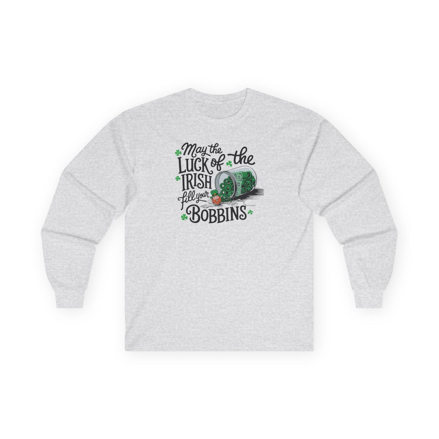 An Ash long-sleeve t-shirt featuring a festive design with shamrocks, a spool of green thread, and the phrase 'May the Luck of the Irish Fill Your Bobbins,' perfect for quilters celebrating St. Patrick’s Day.