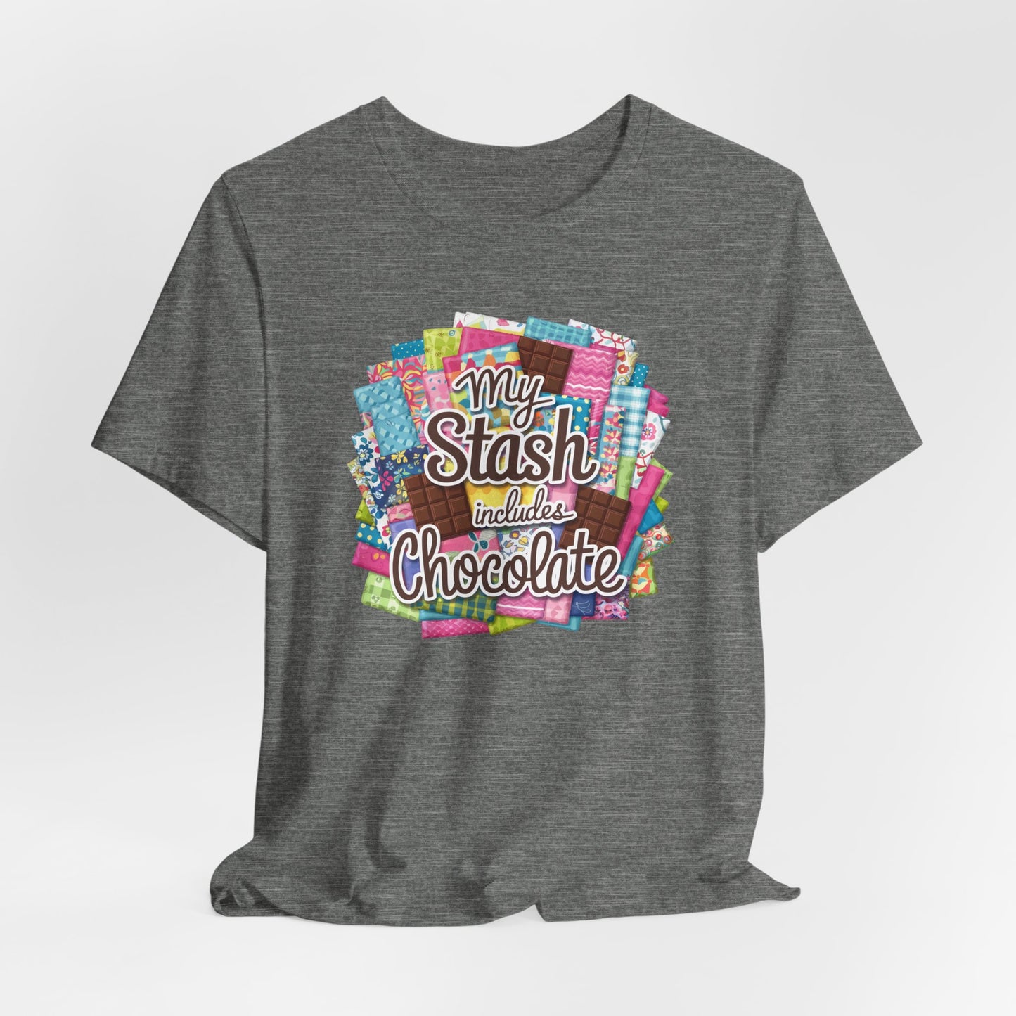 A Deep Heather t-shirt featuring a colorful design of a fabric stash mixed with chocolate bars and the phrase 'My Stash Includes Chocolate,' perfect for quilters and chocolate lovers