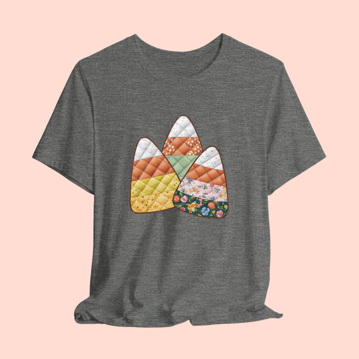 A Halloween Quilting T-Shirt featuring three large candy corn shapes made of quilted fabrics with various patterns. Each candy corn section features different quilting motifs in autumn colors. Playful take on Halloween candy and quilting craft.