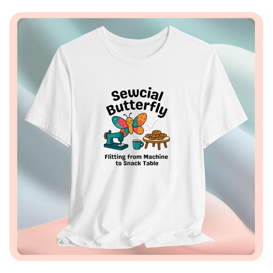 A A t-shirt with a colorful design showing a patchwork butterfly flying between a sewing machine and a table of cookies. Text reads “Sewcial Butterfly – Flitting from Machine to Snack Table.” Funny gift for quilters