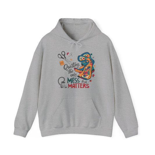 A Sport Grey funny Hoodie with the phrase Quilting, the Only Mess that Matters and illustrations of fabric scraps, scissors, and a vacuum cleaner. Colorful quilt patterns swirl around the text, creating a playful and relatable design for quilting enthusiasts.