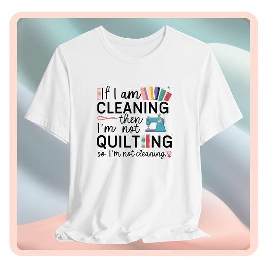 A funny quilting T-Shirt with the phrase If I am Cleaning then I'm not Quilting in a bold and cheerful font with images of quilting icons and supplies