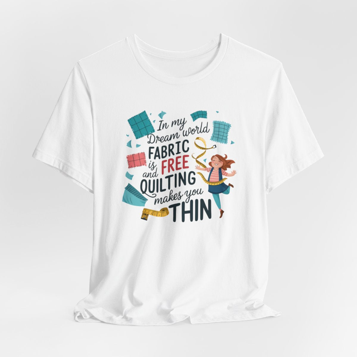 A White funny quilting T-Shirt with the phrase Fabric is Free and Quilting Makes You Thin in a fun font with a cheerful quilter jumping for joy