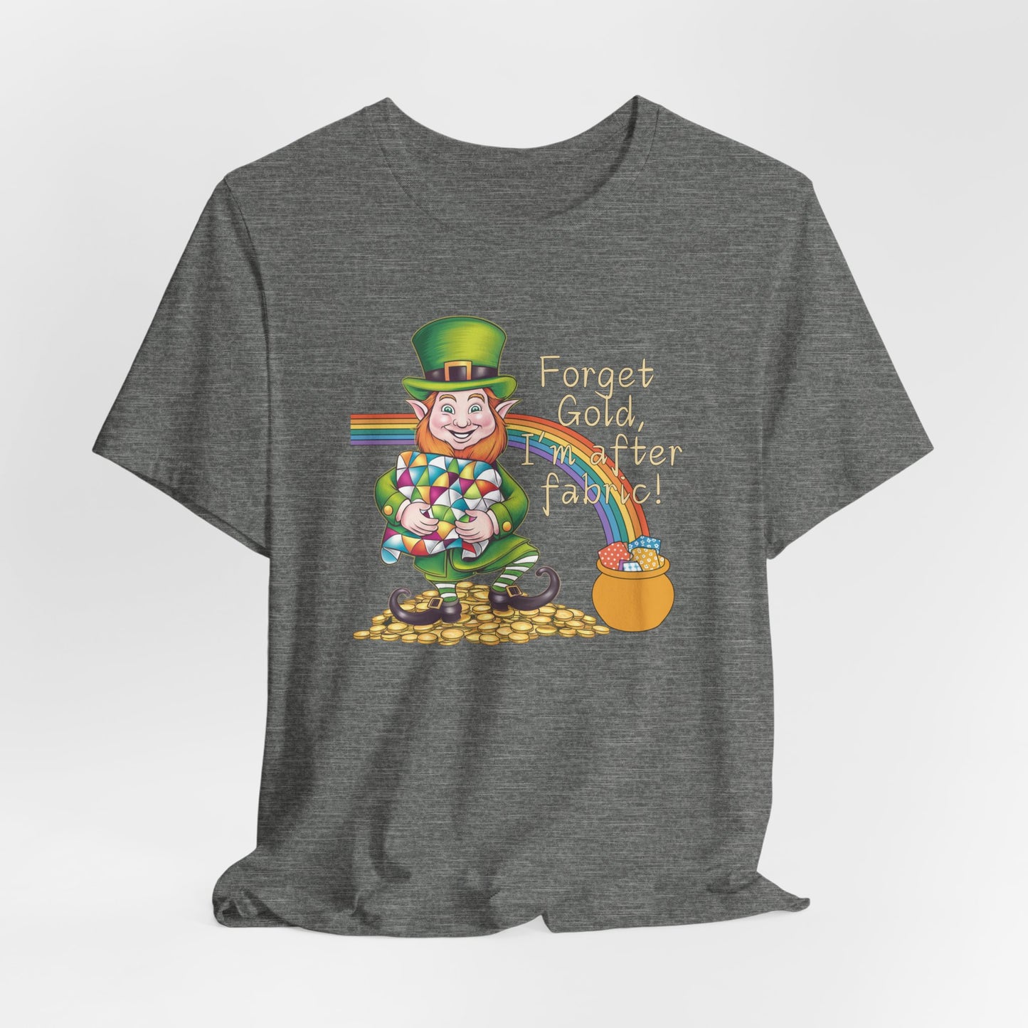 A Deep Heather short-sleeve t-shirt featuring a cheerful leprechaun holding a quilt, sitting on gold coins, with a rainbow leading to a fabric-filled pot and the phrase 'Forget Gold, I’m After Fabric!' Perfect for quilters celebrating St. Patrick’s Day.