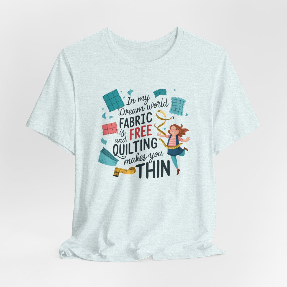 A Heather Ice Blue funny quilting T-Shirt with the phrase Fabric is Free and Quilting Makes You Thin in a fun font with a cheerful quilter jumping for joy