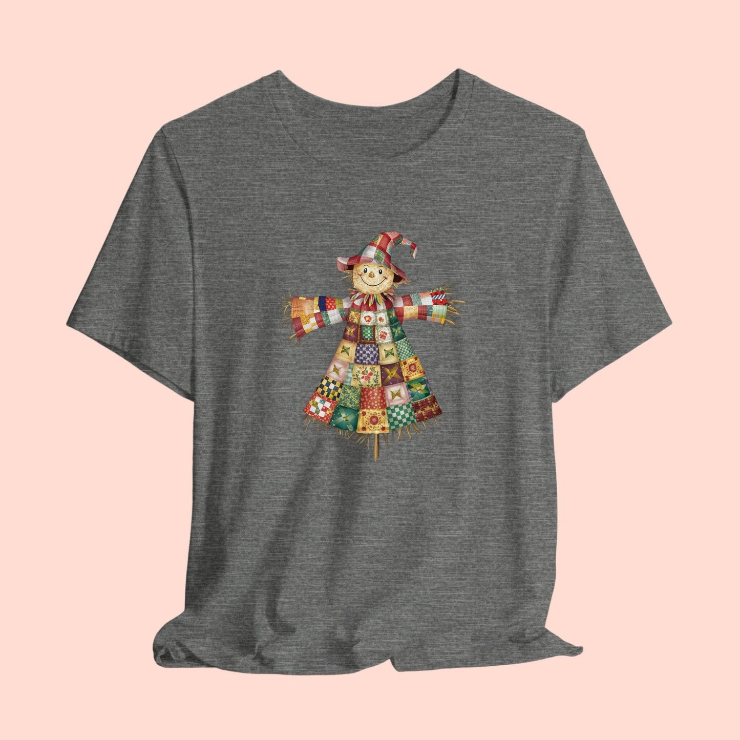 A thanksgiving  quilting t-shirt featuring a smiling scarecrow made entirely of colorful quilt patterns. Wearing a patchwork hat and clothes with various quilt designs. Straw details on hands and neck. Cheerful autumn-themed illustration celebrating quilting craft.