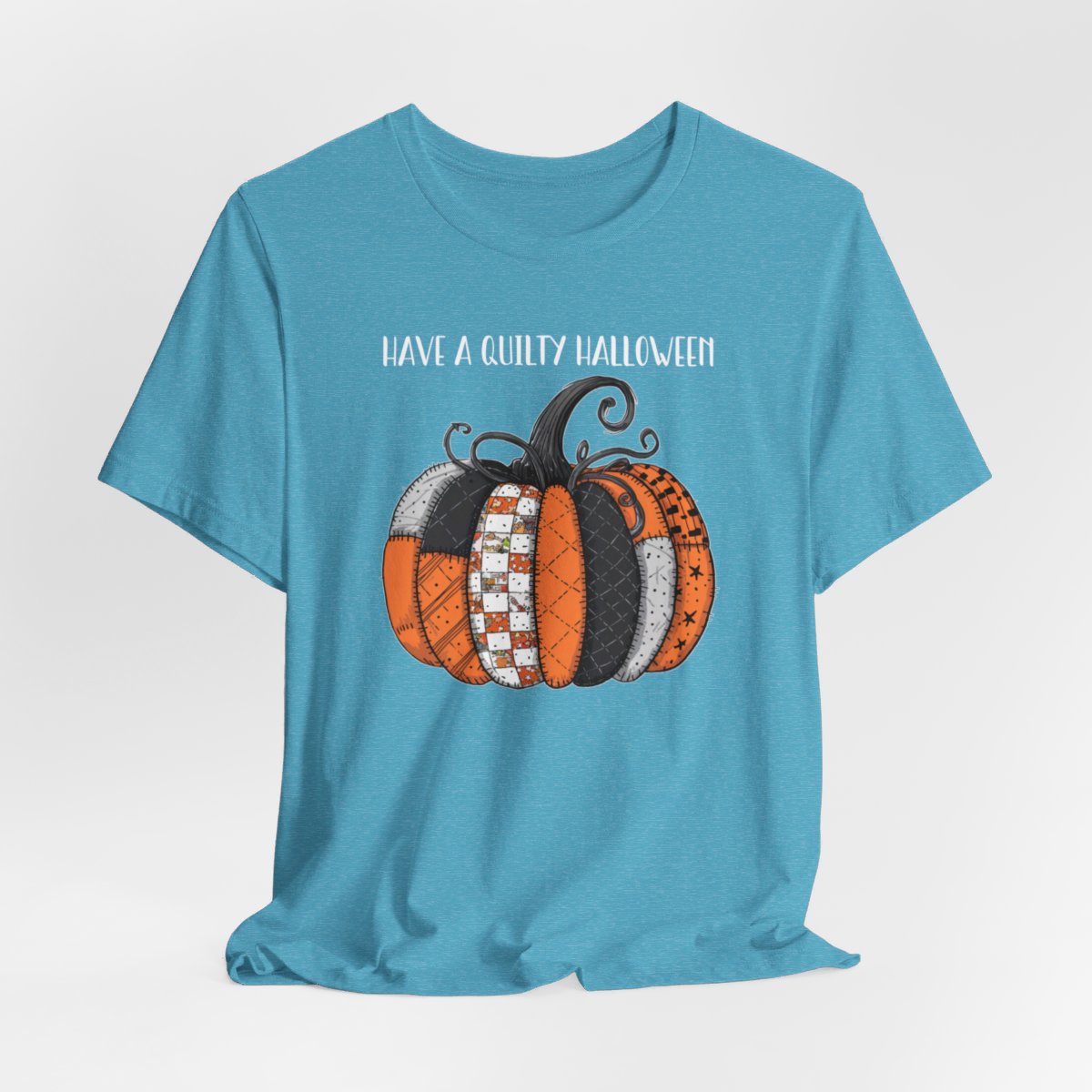 A Heather Aqua Halloween Quilting T-Shirt featuring patchwork pumpkin with various quilt patterns. Mix of Halloween and traditional quilt motifs. Intricate stitching details. Text reads "Have a Quilty Halloween". Ideal for quilters who love Halloween.