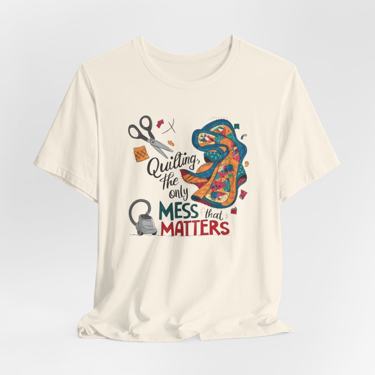 A Natural fun T-Shirt with the phrase Quilting, the Only Mess that Matters and illustrations of fabric scraps, scissors, and a vacuum cleaner. Colorful quilt patterns swirl around the text, creating a playful and relatable design for quilting enthusiasts.