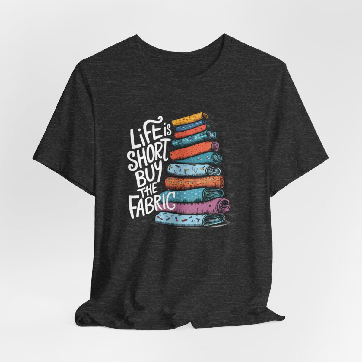 A Dark Grey Heather fun T-Shirt with the phrase Life is Short, Buy the Fabric with the label 'Life is Short, Buy the Fabric' next to a graphic of a fun pile of fabric