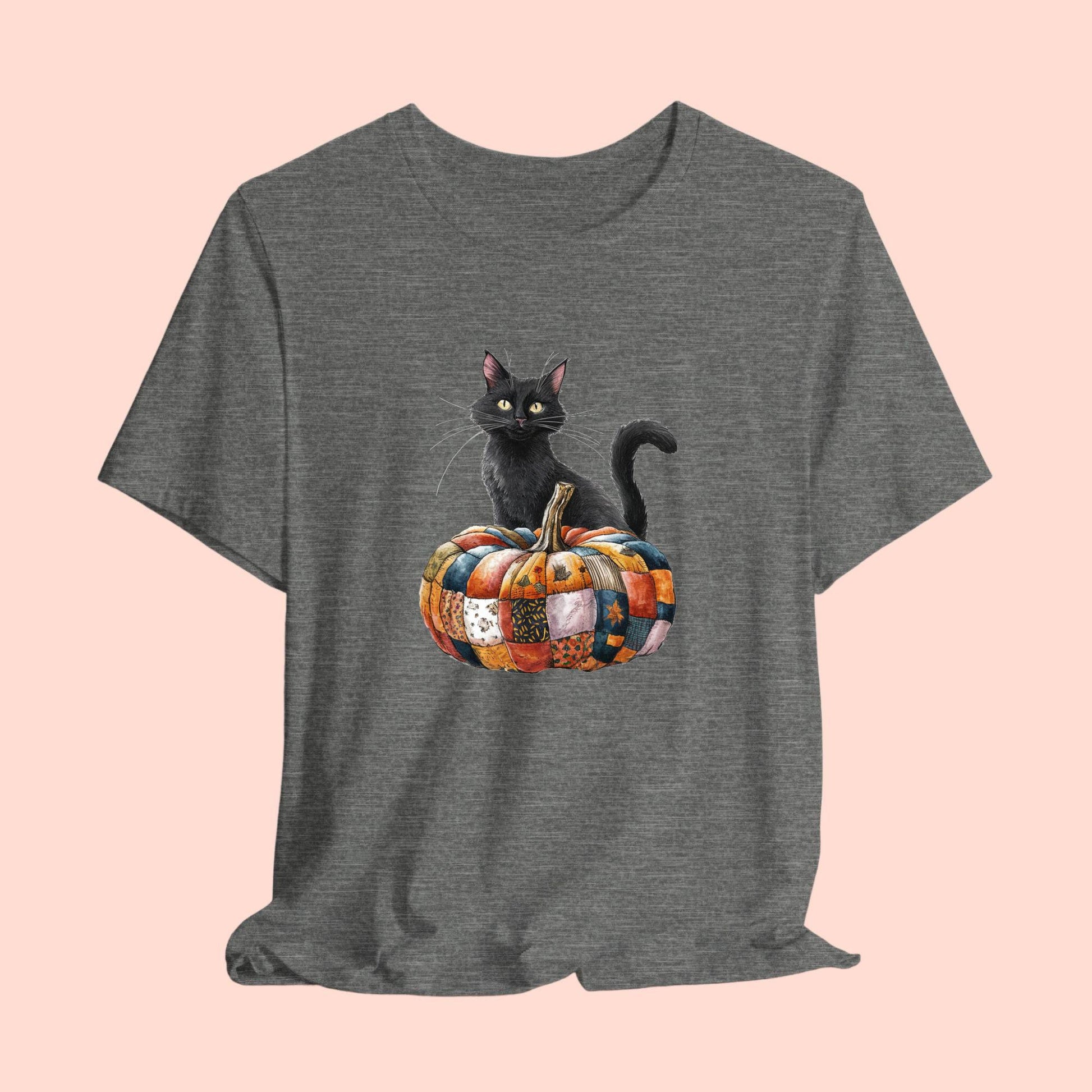 A Halloween Quilting T-Shirt featuring a black cat sitting on colorful patchwork quilt pumpkin. Cat has yellow eyes and long whiskers. Pumpkin features various quilt patterns in autumn colors. Halloween-themed t-shirt design for quilting enthusiasts.