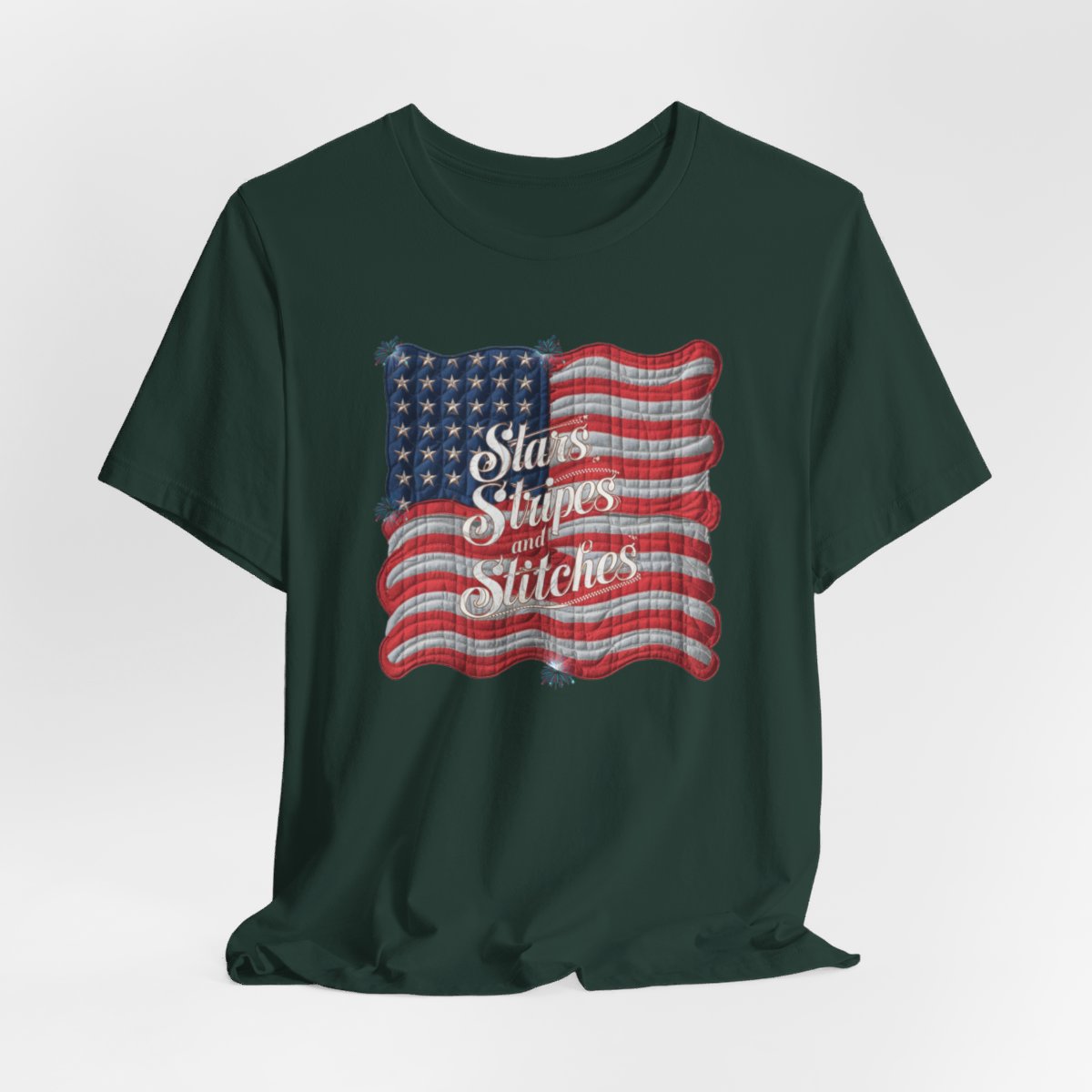 A Forest T-shirt featuring quilted American flag design with text "Stars Stripes and Stitches" overlaid in stylized, patriotic font. Fireworks accent the corners.