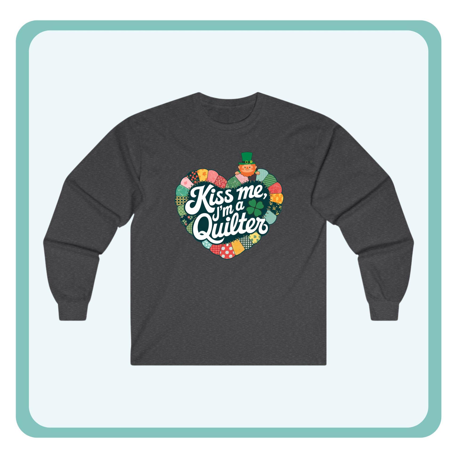 A long-sleeve t-shirt featuring a heart-shaped patchwork quilt design with shamrocks, a leprechaun, and the phrase 'Kiss Me, I’m a Quilter,' perfect for St. Patrick’s Day quilting fun.