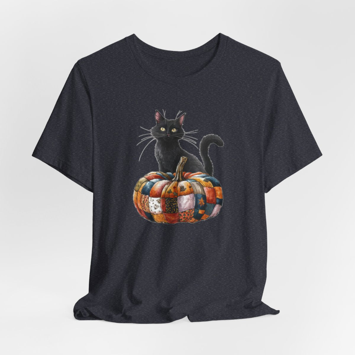 A Heather Navy Halloween Quilting T-Shirt featuring a black cat sitting on colorful patchwork quilt pumpkin. Cat has yellow eyes and long whiskers. Pumpkin features various quilt patterns in autumn colors. Halloween-themed t-shirt design for quilting enthusiasts.