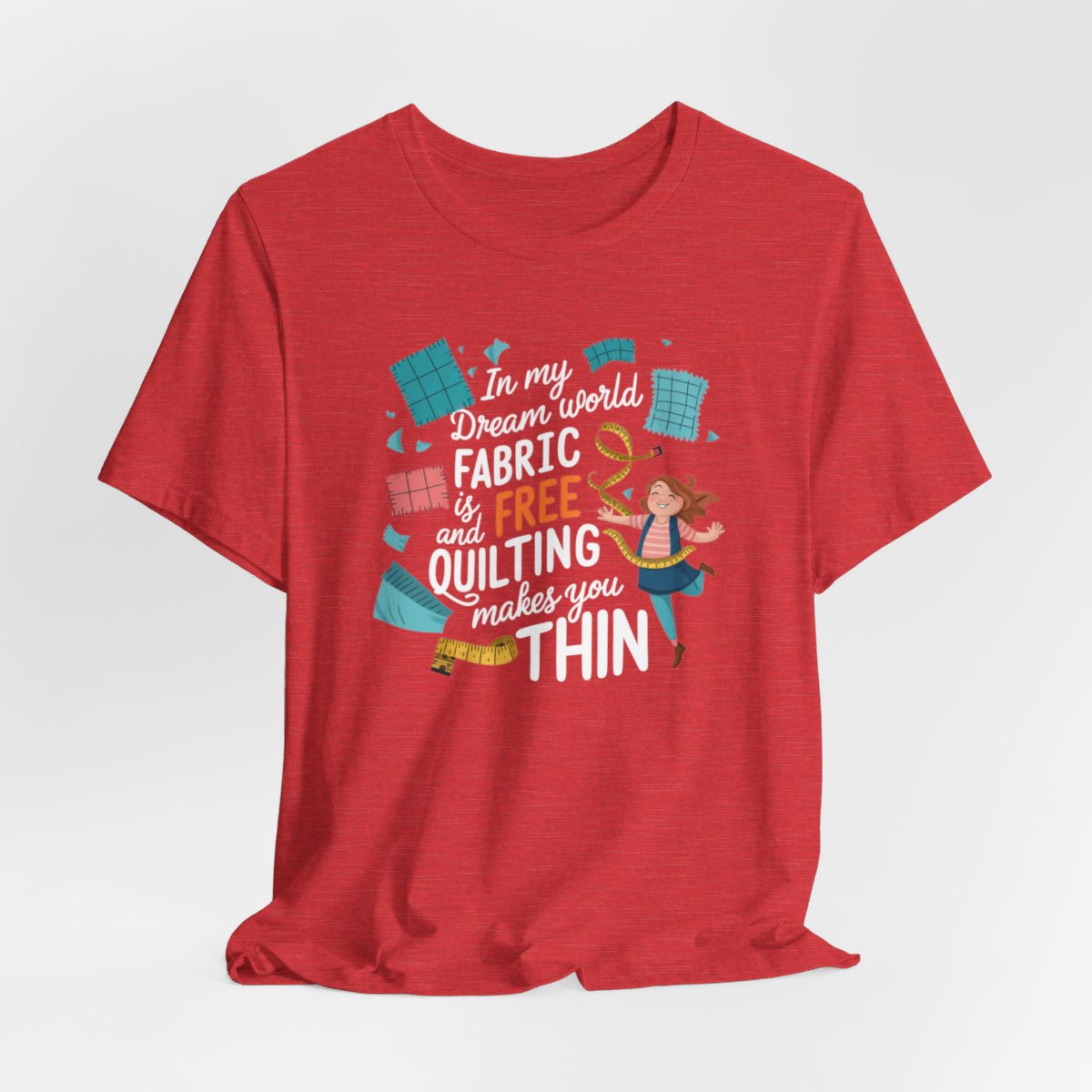 A Heather Red funny quilting T-Shirt with the phrase Fabric is Free and Quilting Makes You Thin in a fun font with a cheerful quilter jumping for joy