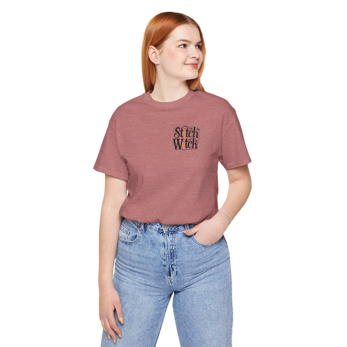 A Heather Mauve Halloween Quilting T-Shirt featuring "Stitch Witch" text in Halloween-themed typography. Jack-o'-lanterns, spiderwebs, and bats decorate the letters. The "i" in "Stitch" resembles a sewing needle. Ideal for quilters who love Halloween.