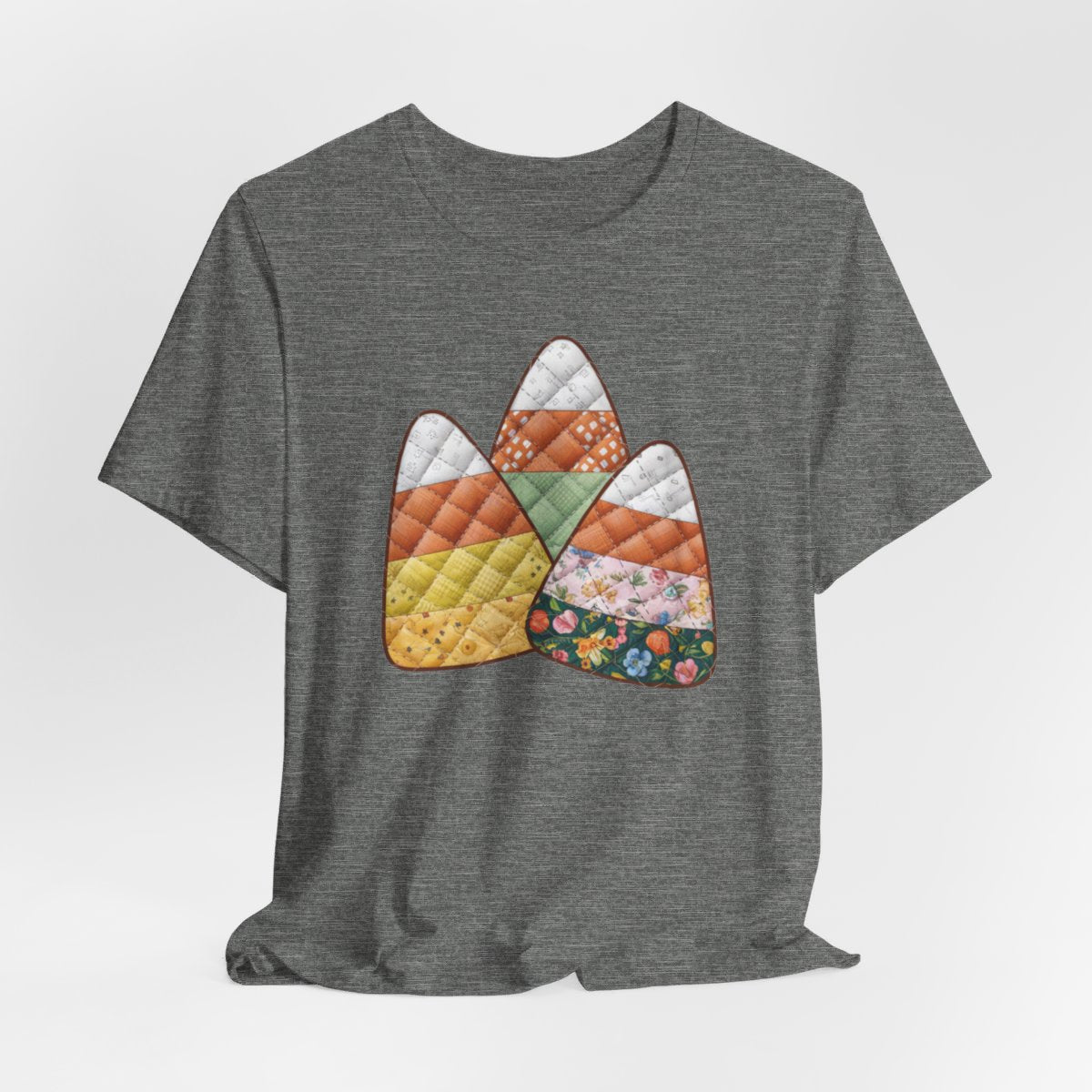 A Deep Heather Halloween Quilting T-Shirt featuring three large candy corn shapes made of quilted fabrics with various patterns. Each candy corn section features different quilting motifs in autumn colors. Playful take on Halloween candy and quilting craft.