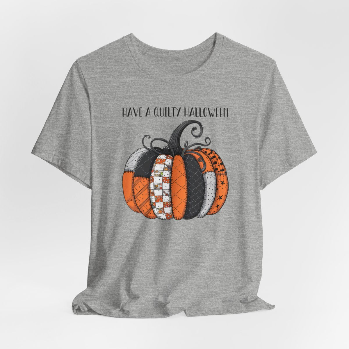 An Athletic Heather Halloween Quilting T-Shirt featuring patchwork pumpkin with various quilt patterns. Mix of Halloween and traditional quilt motifs. Intricate stitching details. Text reads "Have a Quilty Halloween". Ideal for quilters who love Halloween.