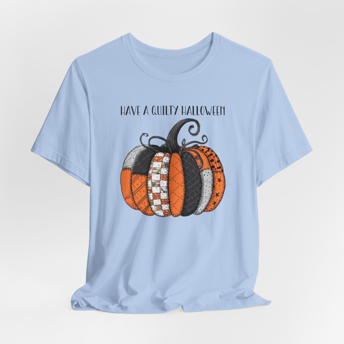 A Baby Blue Halloween Quilting T-Shirt featuring patchwork pumpkin with various quilt patterns. Mix of Halloween and traditional quilt motifs. Intricate stitching details. Text reads "Have a Quilty Halloween". Ideal for quilters who love Halloween.