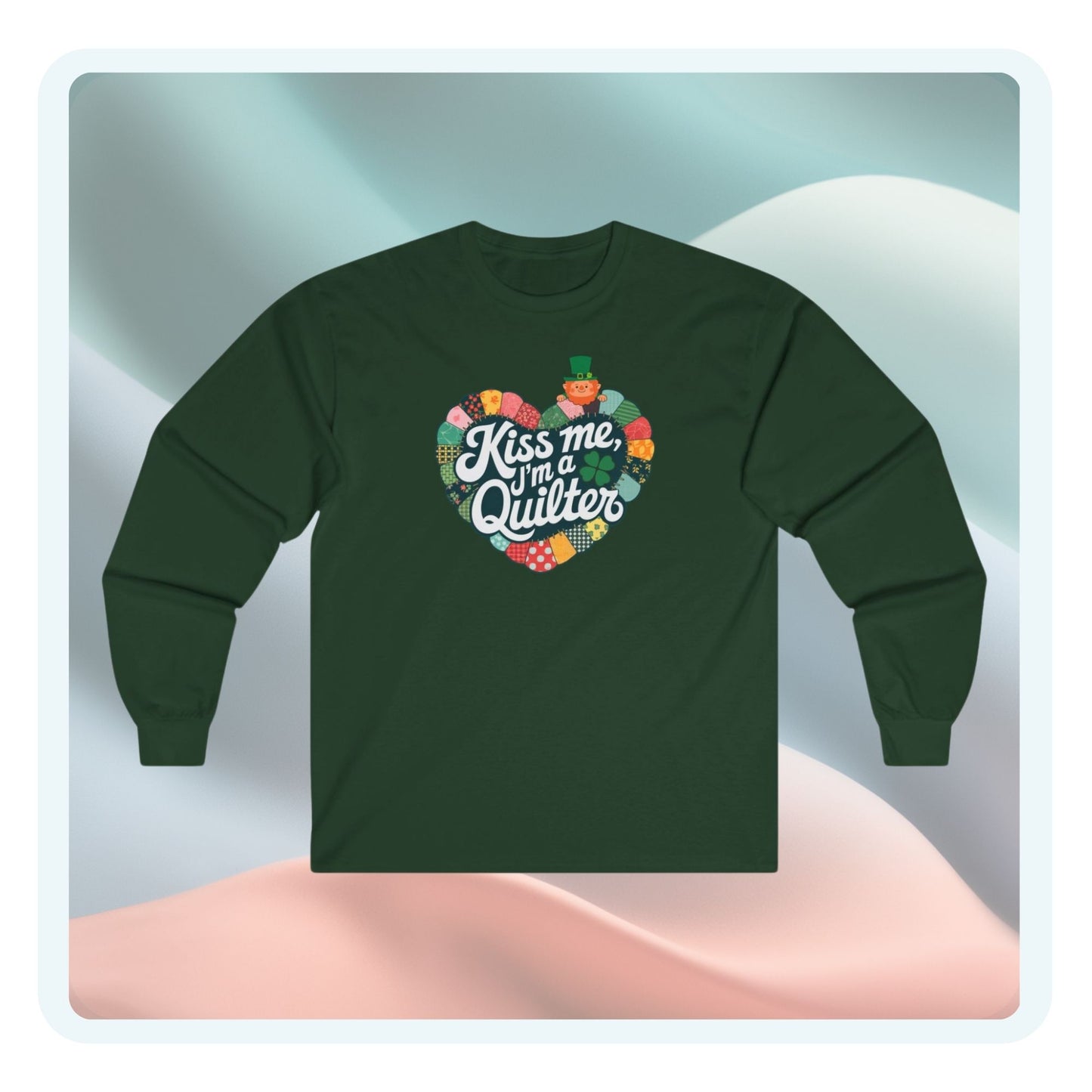 A long-sleeve t-shirt featuring a heart-shaped patchwork quilt design with shamrocks, a leprechaun, and the phrase 'Kiss Me, I’m a Quilter,' perfect for St. Patrick’s Day quilting fun.