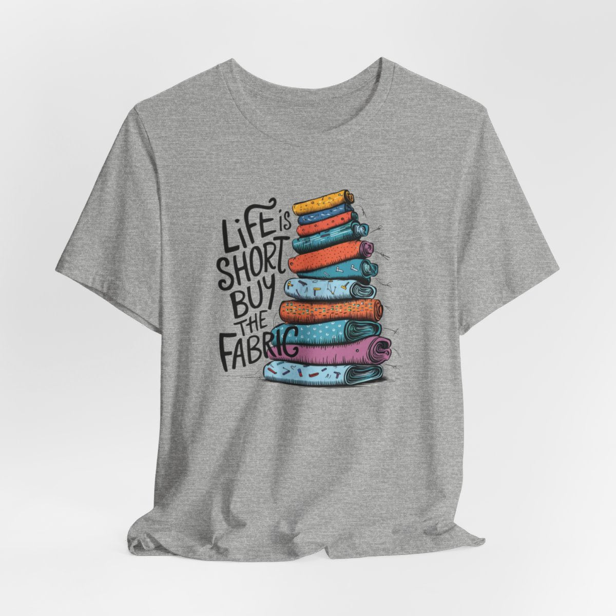 An Athletic Heather fun T-Shirt with the phrase Life is Short, Buy the Fabric with the label 'Life is Short, Buy the Fabric' next to a graphic of a fun pile of fabric