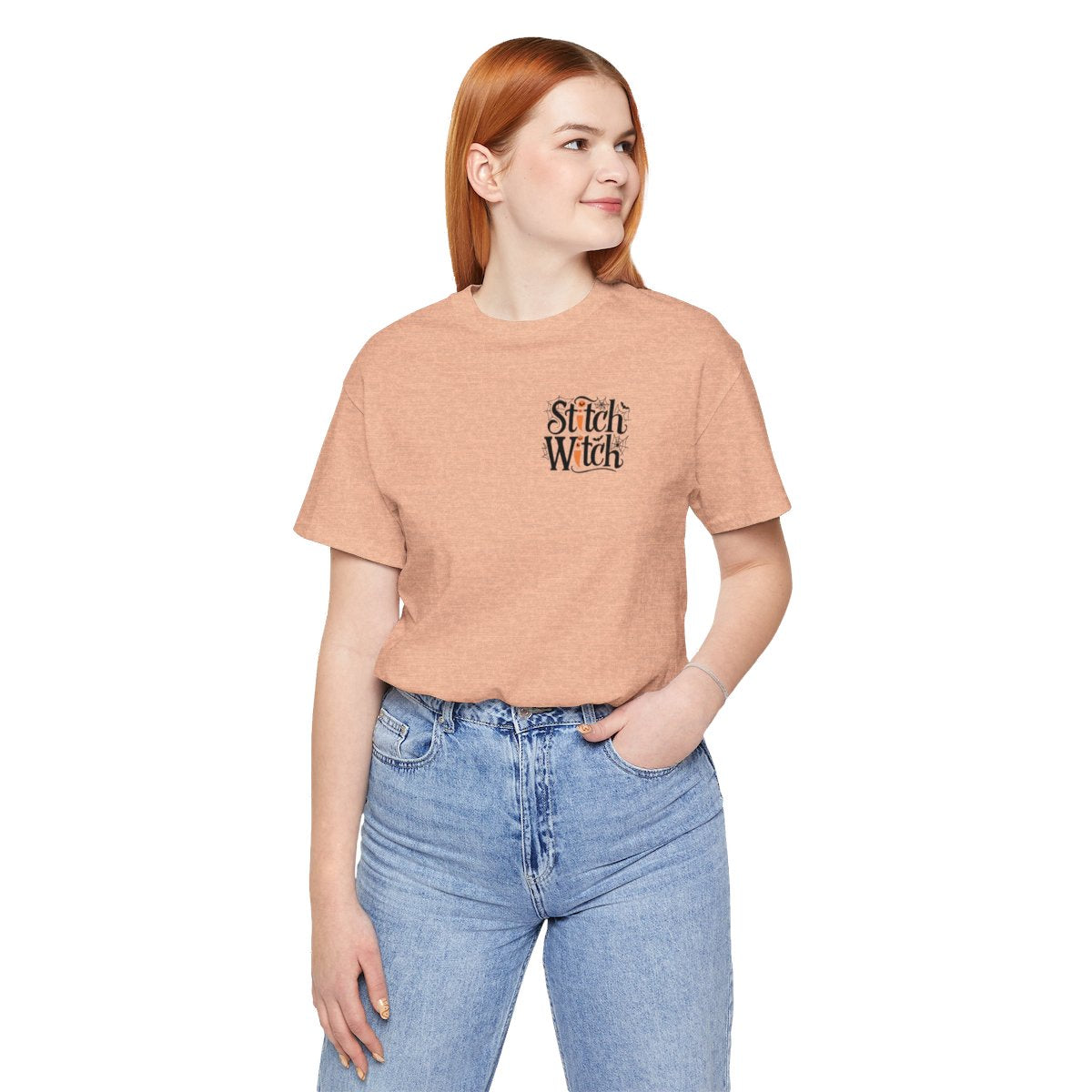 A Heather Peach Halloween Quilting T-Shirt featuring "Stitch Witch" text in Halloween-themed typography. Jack-o'-lanterns, spiderwebs, and bats decorate the letters. The "i" in "Stitch" resembles a sewing needle. Ideal for quilters who love Halloween.