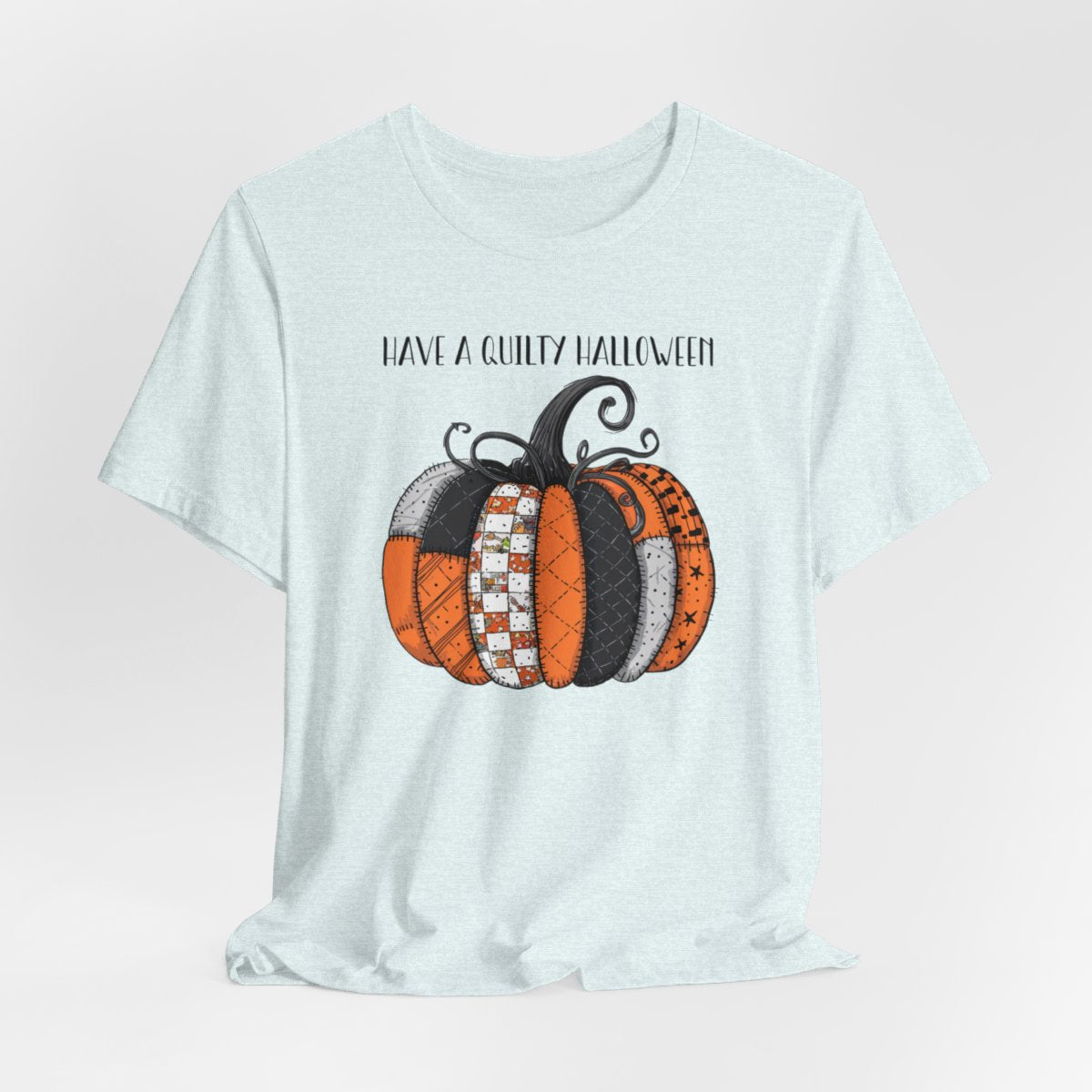 A Heather Ice Blue Halloween Quilting T-Shirt featuring patchwork pumpkin with various quilt patterns. Mix of Halloween and traditional quilt motifs. Intricate stitching details. Text reads "Have a Quilty Halloween". Ideal for quilters who love Halloween.