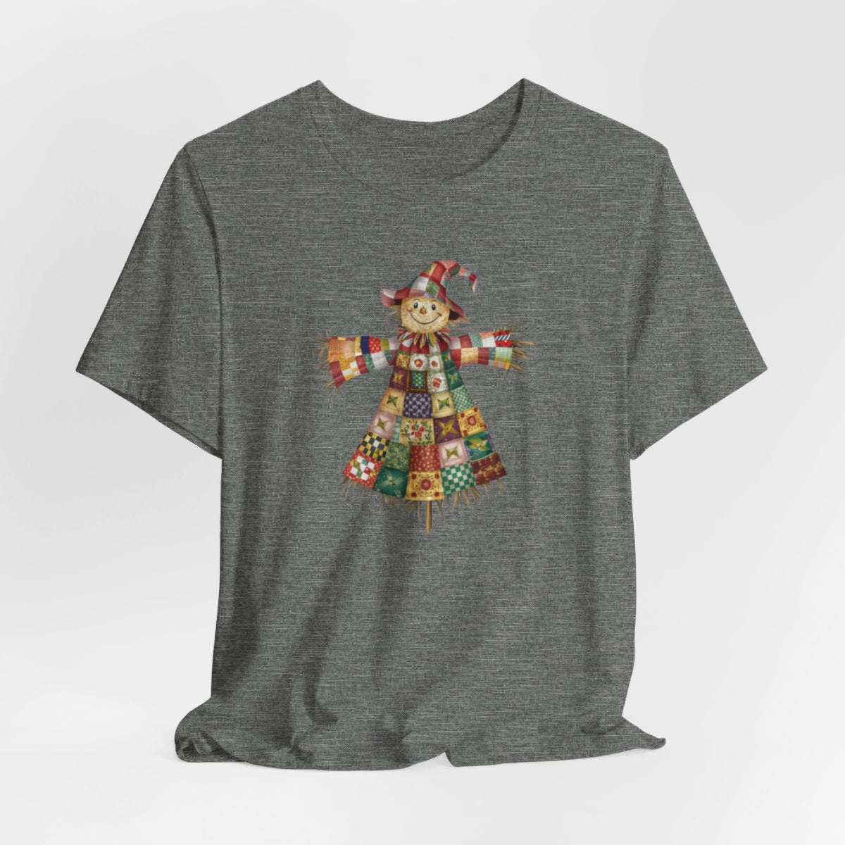 A Deep Heather thanksgiving  quilting t-shirt featuring a smiling scarecrow made entirely of colorful quilt patterns. Wearing a patchwork hat and clothes with various quilt designs. Straw details on hands and neck. Cheerful autumn-themed illustration celebrating quilting craft.