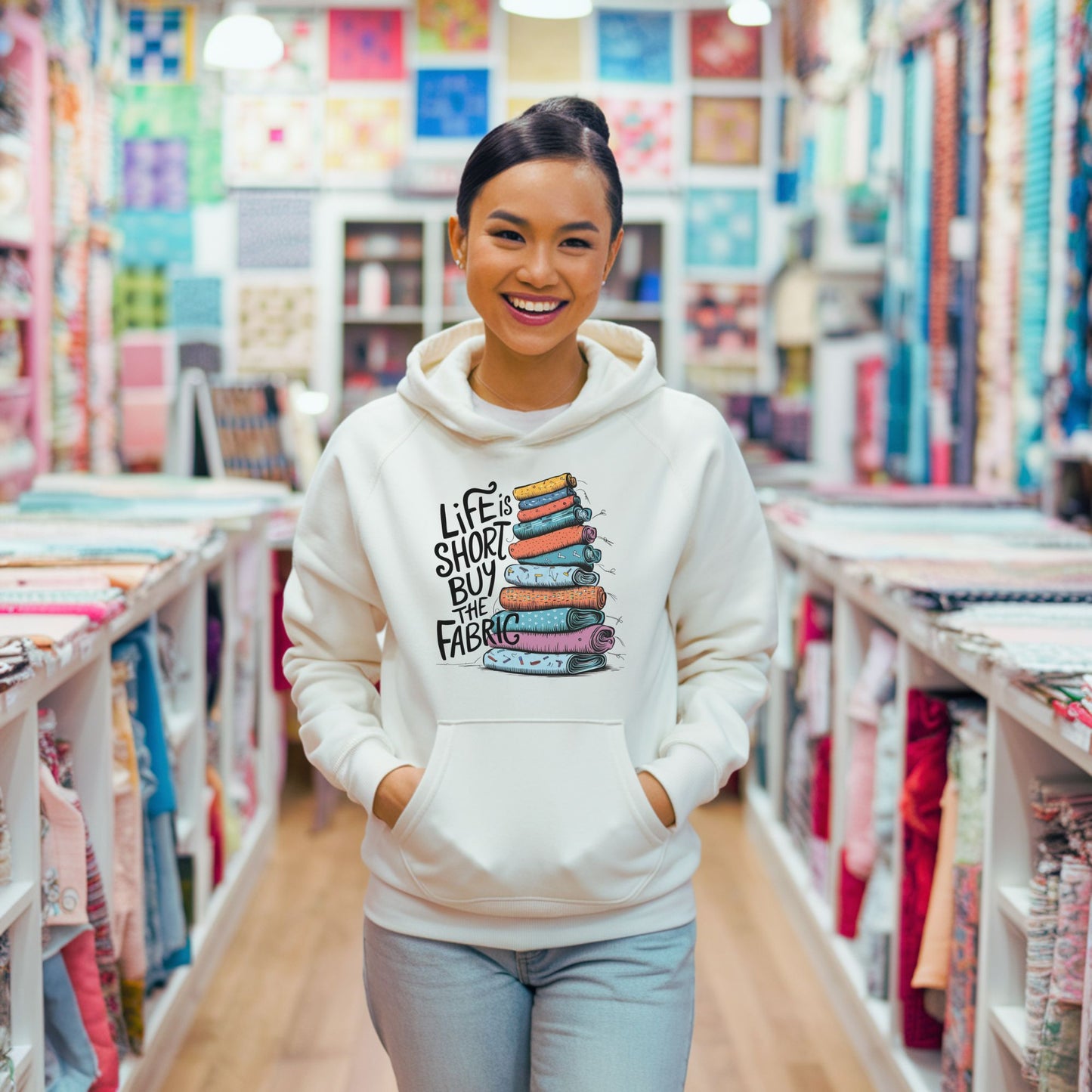 A funny Hoodie with the phrase Life is Short, Buy the Fabric with the label 'Life is Short, Buy the Fabric' next to a graphic of pile of fabric