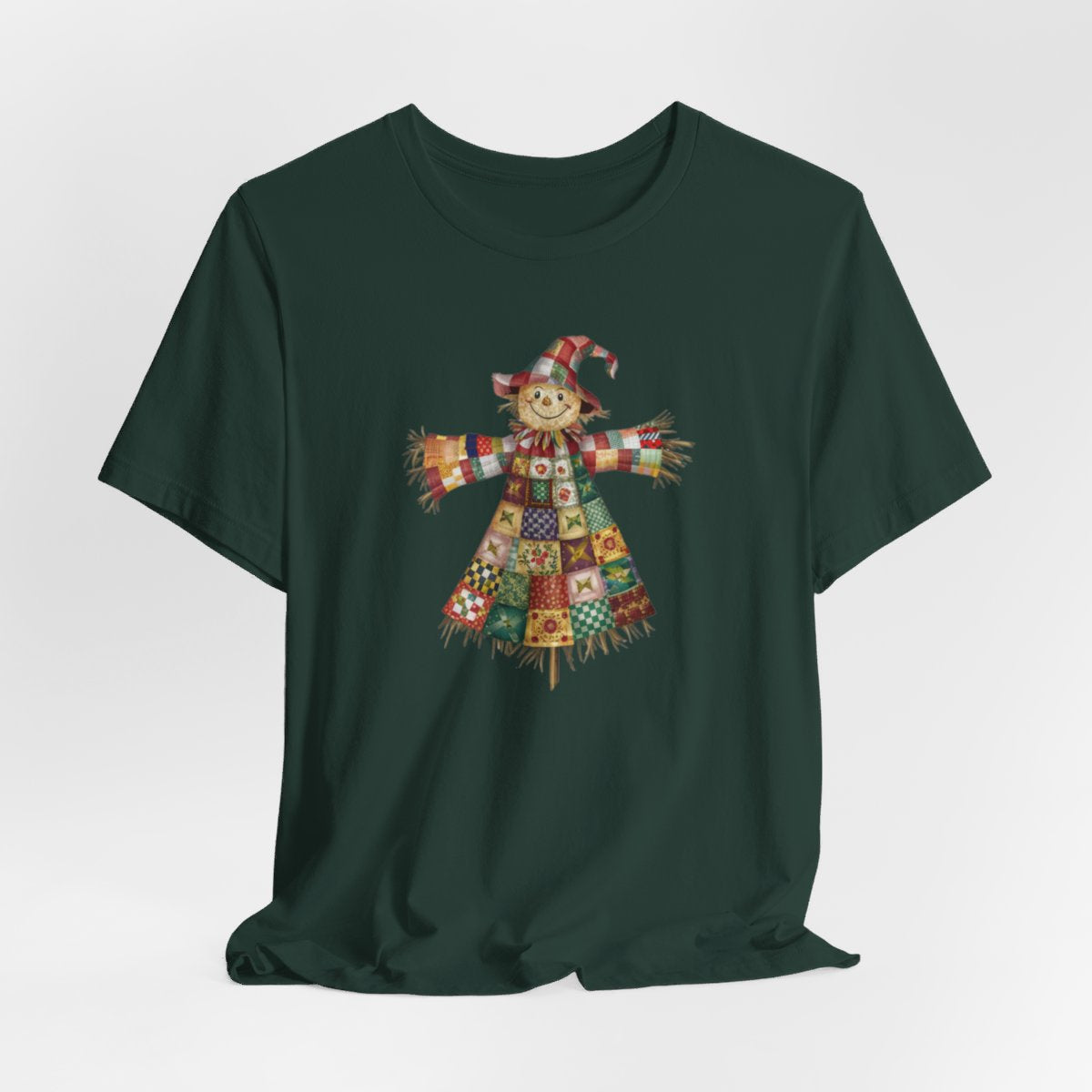 A Forest thanksgiving  quilting t-shirt featuring a smiling scarecrow made entirely of colorful quilt patterns. Wearing a patchwork hat and clothes with various quilt designs. Straw details on hands and neck. Cheerful autumn-themed illustration celebrating quilting craft.