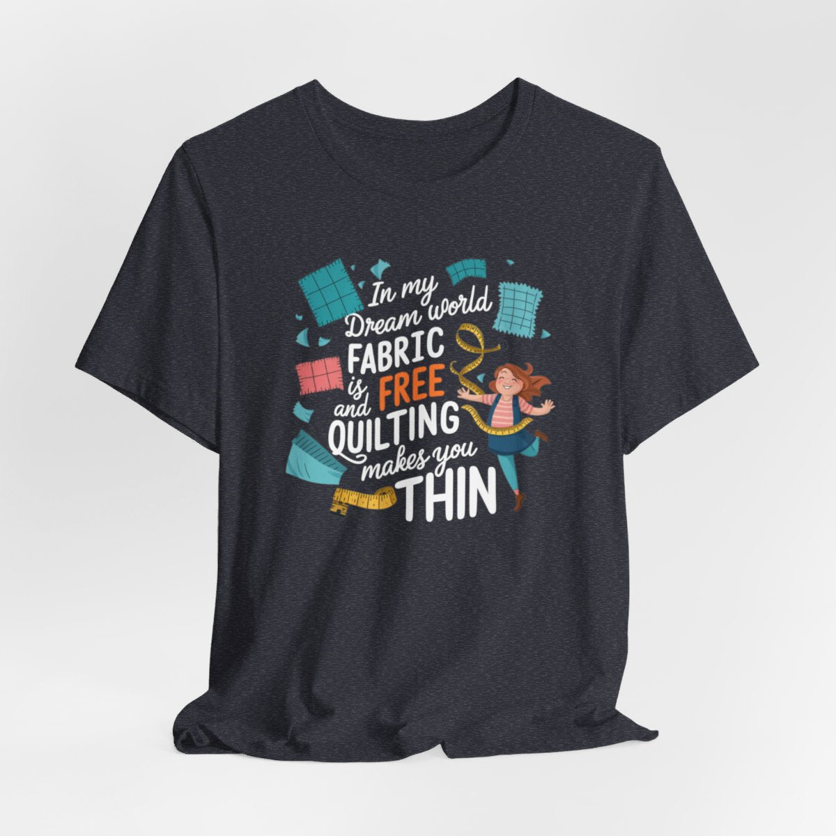 A Heather Navy funny quilting T-Shirt with the phrase Fabric is Free and Quilting Makes You Thin in a fun font with a cheerful quilter jumping for joy