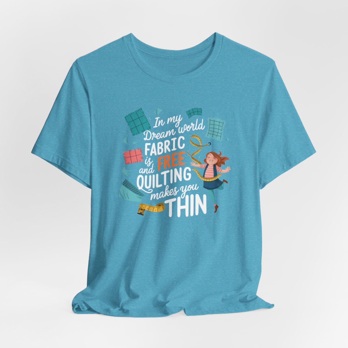 A Heather Aqua funny quilting T-Shirt with the phrase Fabric is Free and Quilting Makes You Thin in a fun font with a cheerful quilter jumping for joy