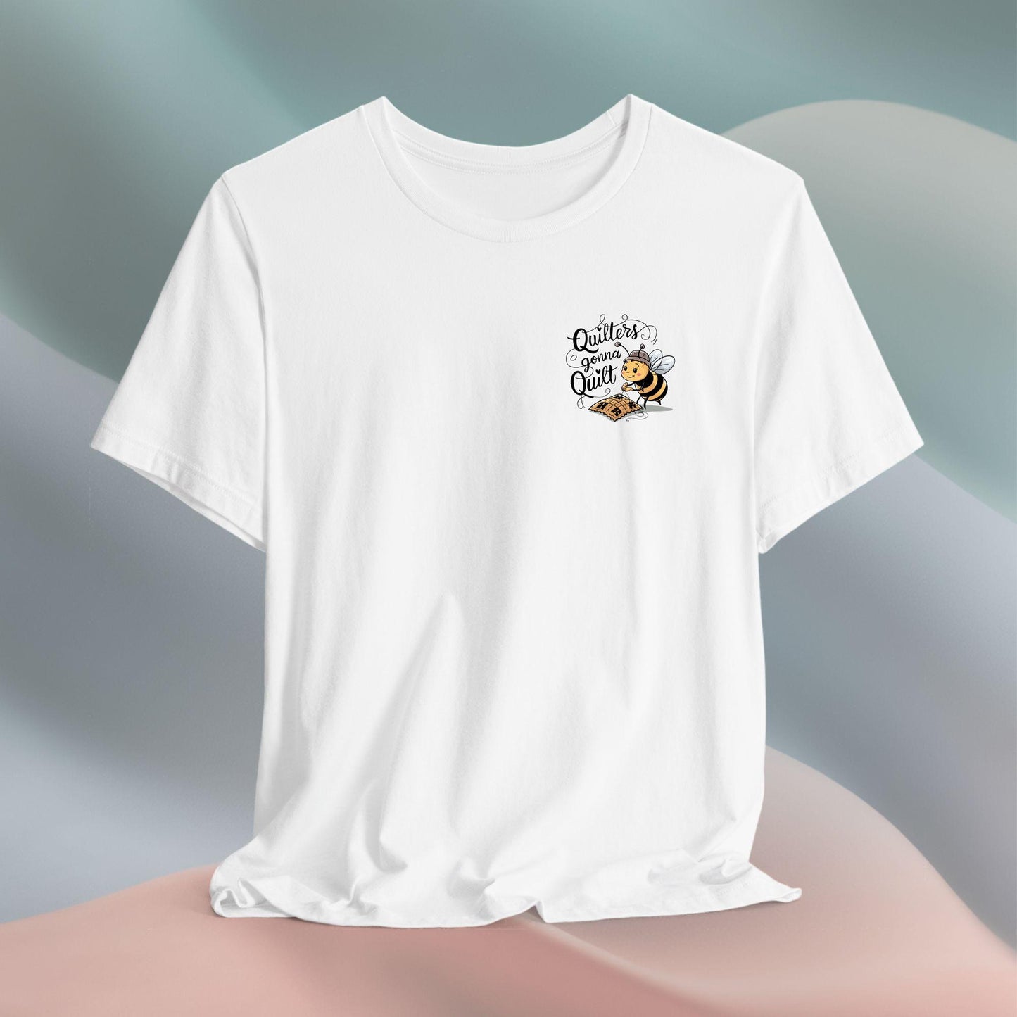 A funny quilting T-shirt design featuring a cartoon bee working on a quilt with the text "Quilters Gonna Quilt". The whimsical illustration and bold lettering capture the determination and passion of dedicated quilters.