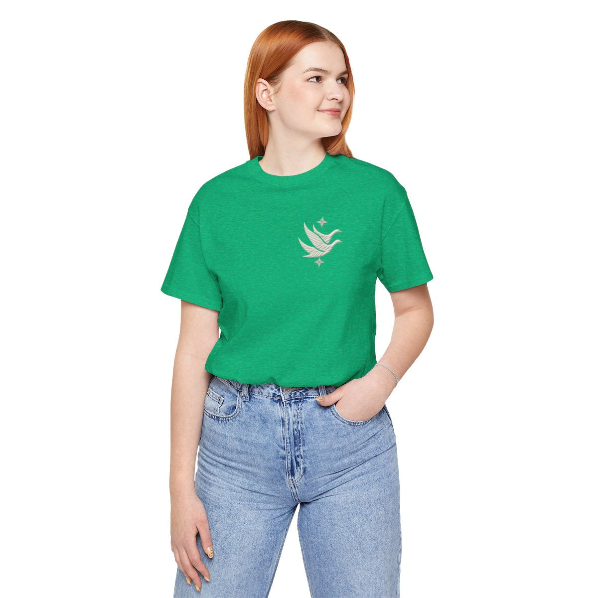 A Heather Kelly T-shirt featuring two stylized white geese in flight, with outstretched wings. The geese are composed of intricate geometric patterns resembling quilt stitching. Two eight-pointed stars frame the scene, one above and one below the geese, adding a celestial element to the peaceful composition.