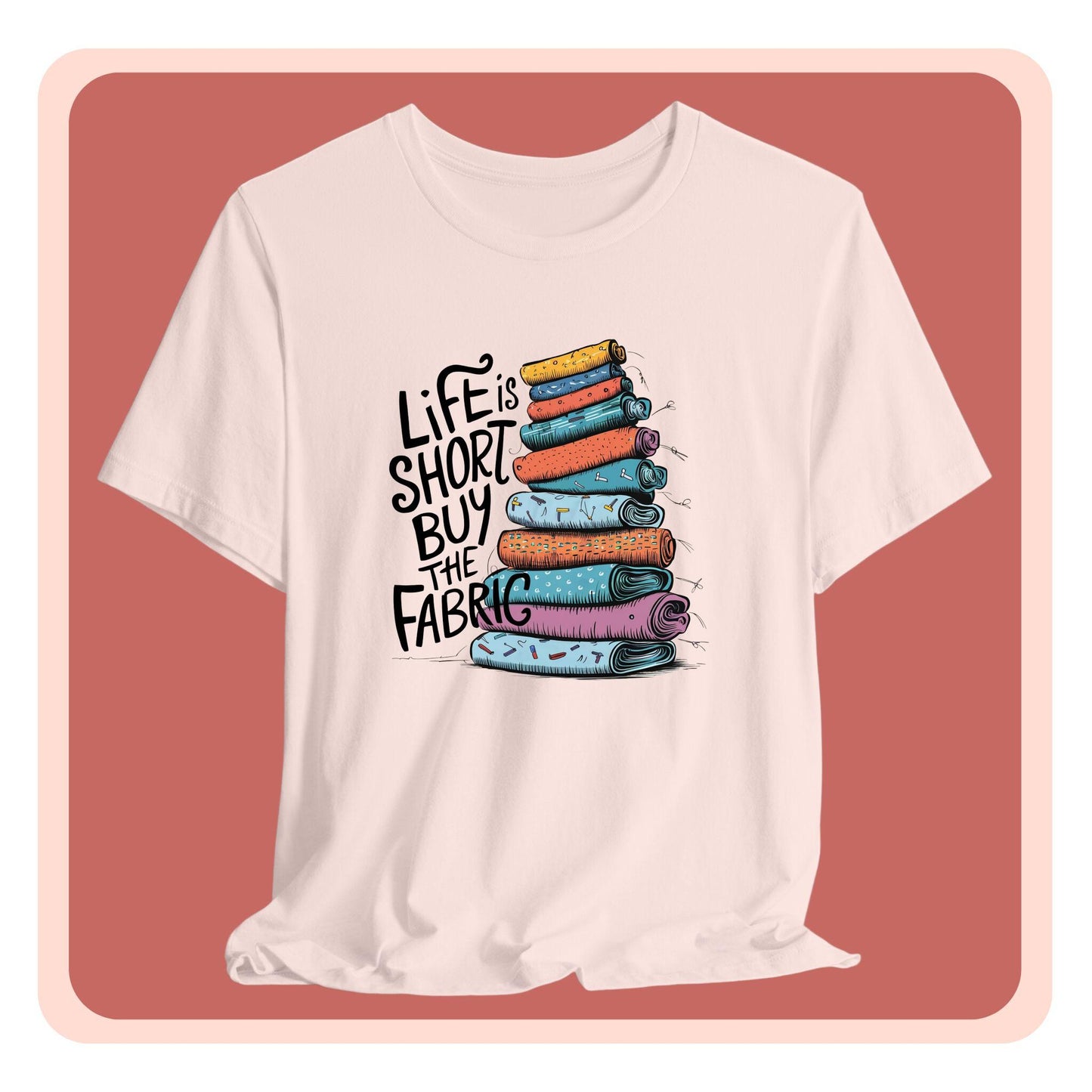 A fun T-Shirt with the phrase Life is Short, Buy the Fabric with the label 'Life is Short, Buy the Fabric' next to a graphic of a fun pile of fabric